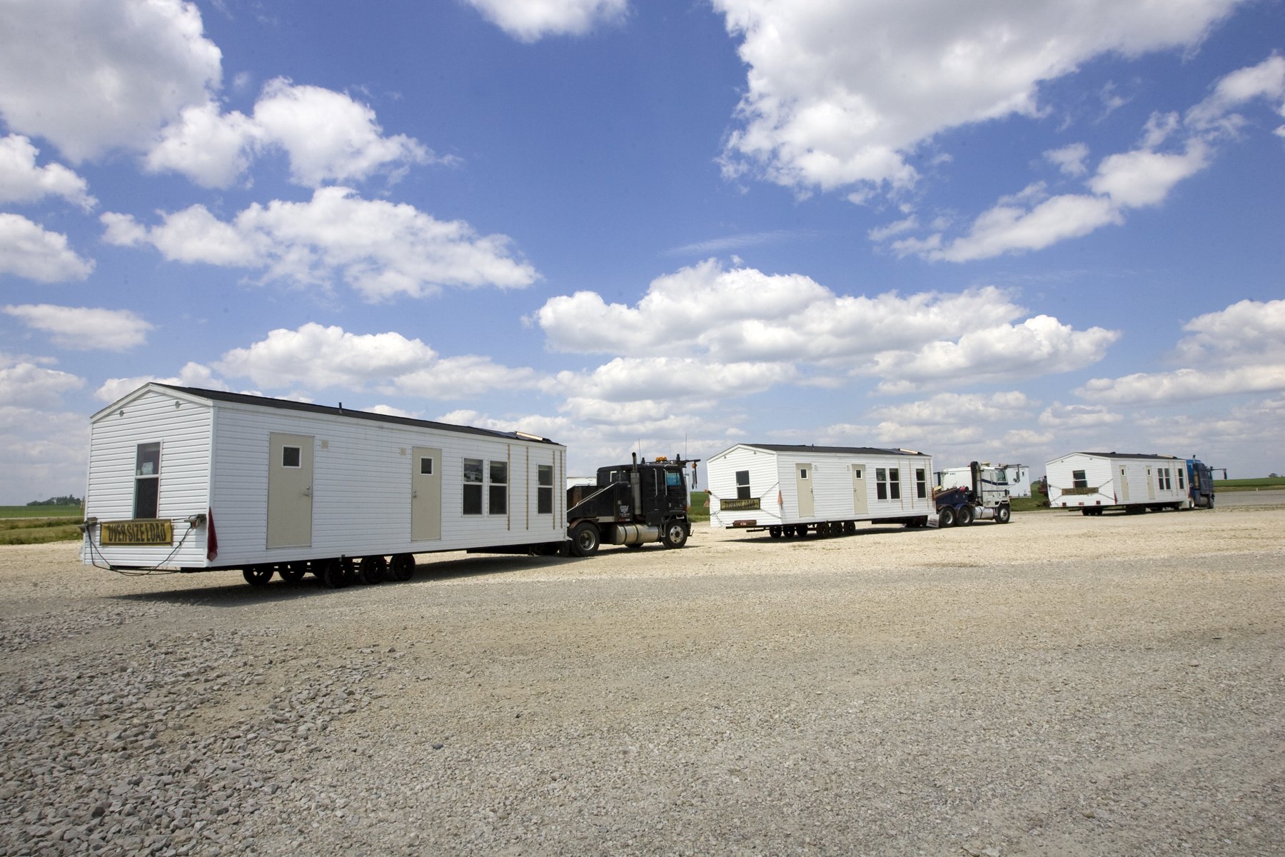 Manufactured homes on their chassis arriving at a staging yard